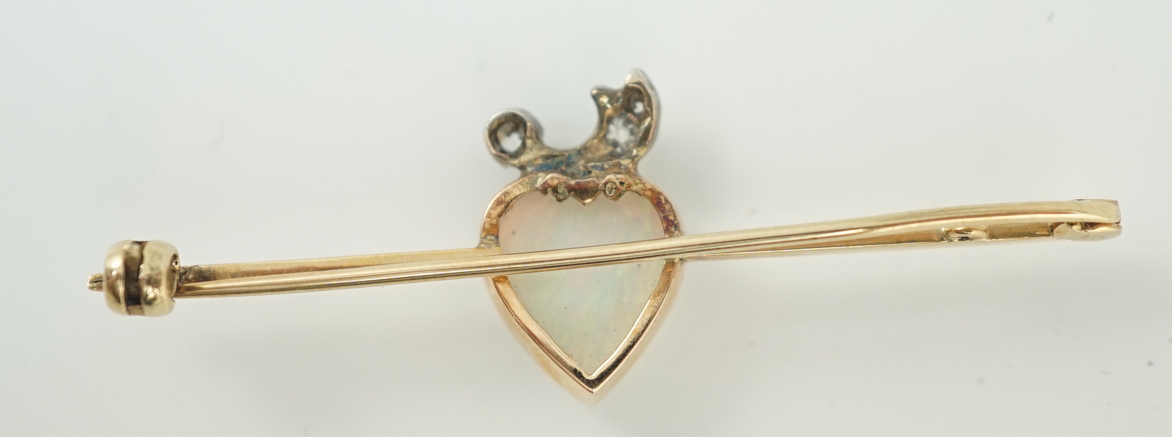 An early 20th century gold, heart shaped white opal and six stone diamond set bar brooch